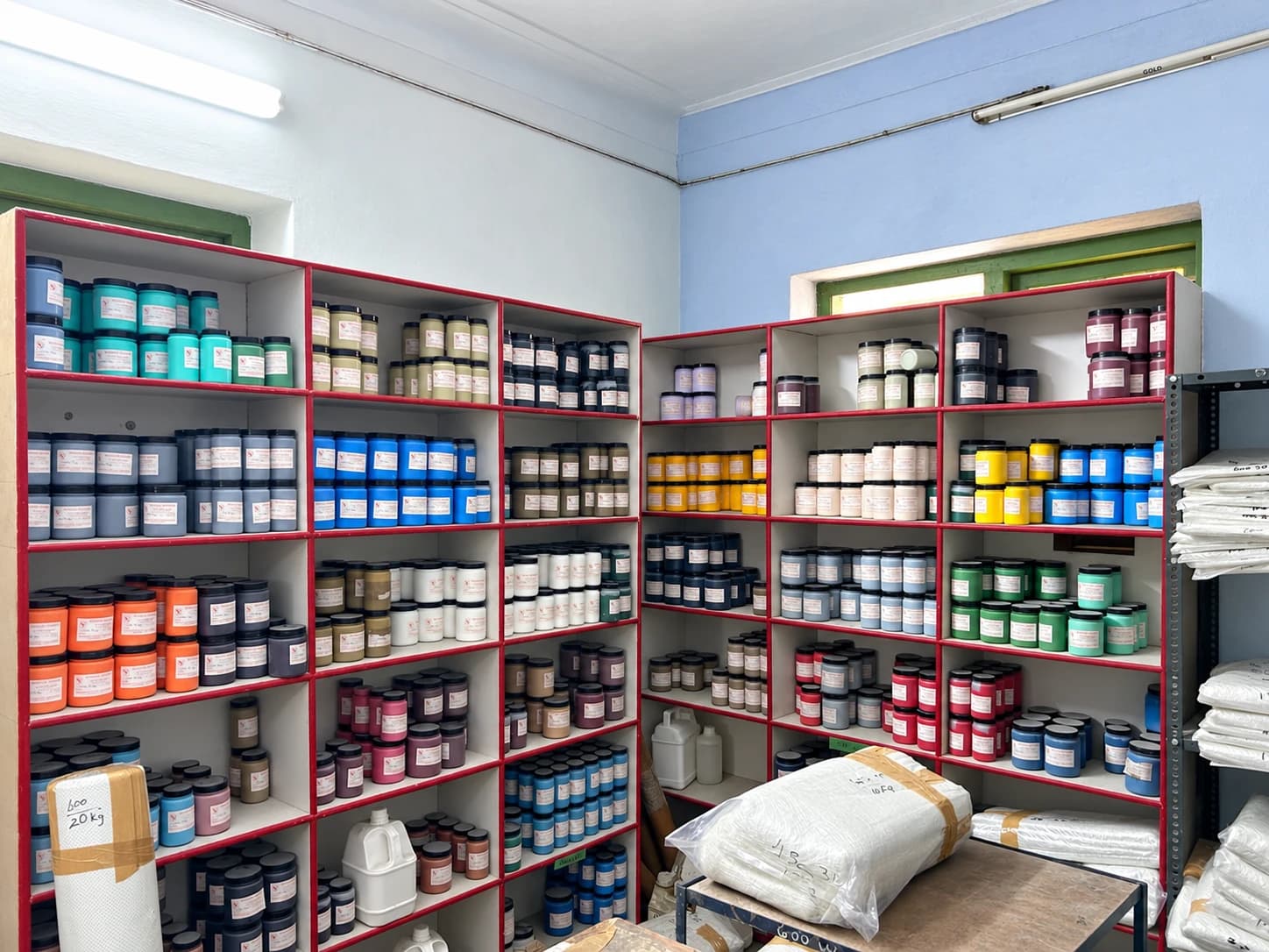 Rows of coloured pigment jars on shelves in the Covai Seenu godown