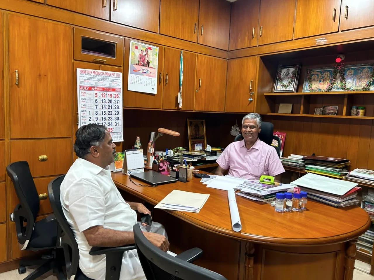 Two Covai Seenu staff members discussing work at the office